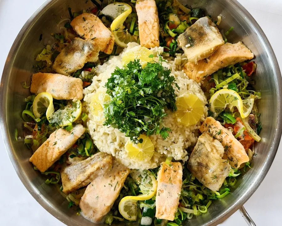 Meerespfanne mit Lachs, Fischfilets, Risotto und Zitrone in der Servierpfanne