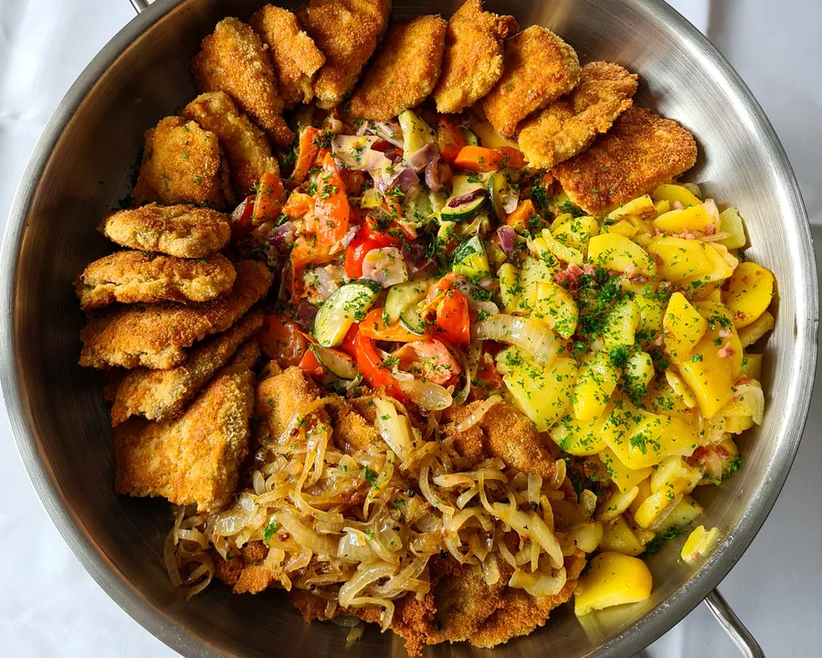 Schnitzelpfanne mit Bratkartoffeln und Paprikagemüse in der Servierpfanne